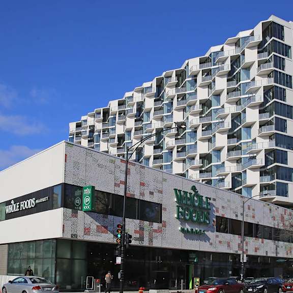 a whole foods store is located in front of a tall building.