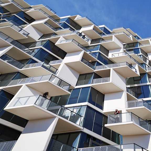 a modern building with white and blue balconies against a blue sky.