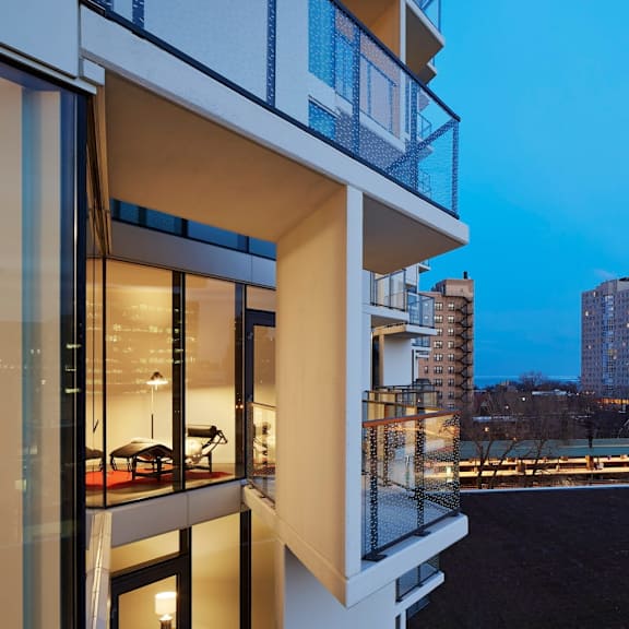 a modern building with a balcony overlooking a cityscape at dusk.