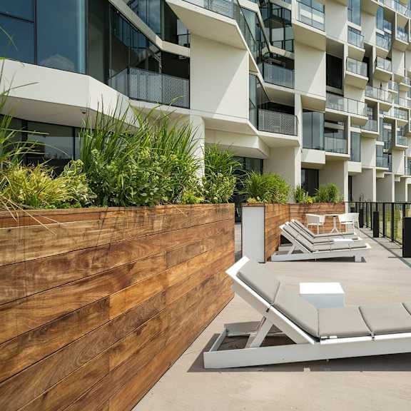 a modern building with a wooden fence and lounge chairs on the balcony.