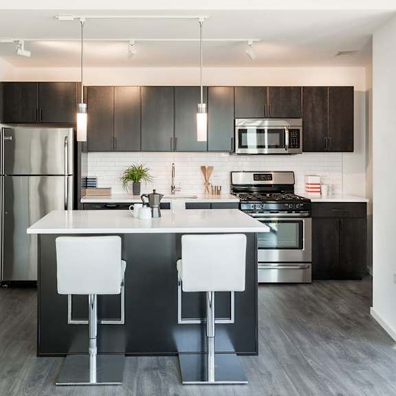 a modern kitchen with a white countertop and black bar stools.