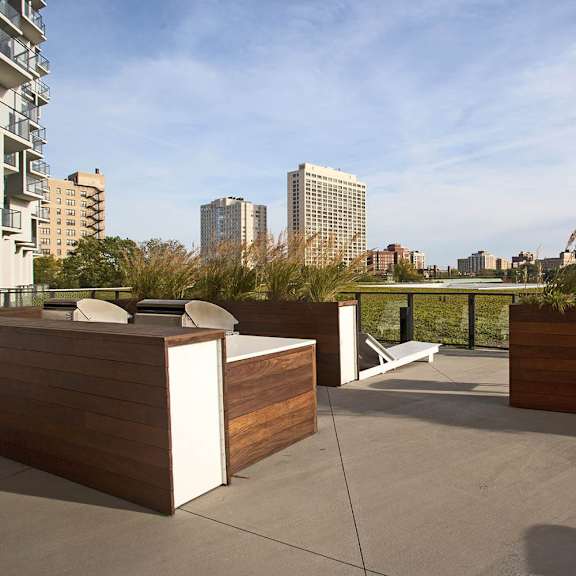 a rooftop patio with wooden furniture and a view of the city.