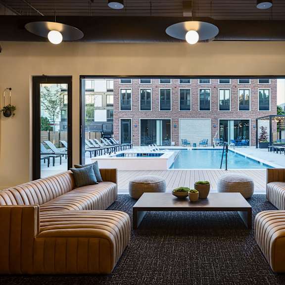 a modern living room with a large window overlooking a pool and buildings outside.