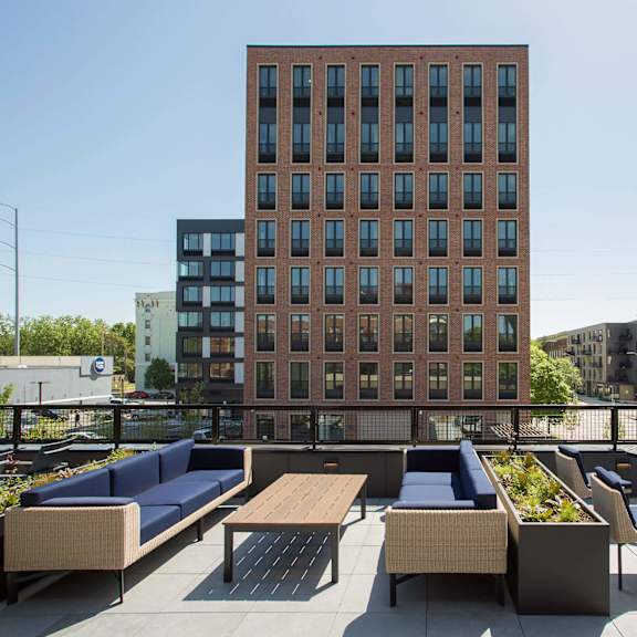 a brown building with a balcony that has a table and chairs.