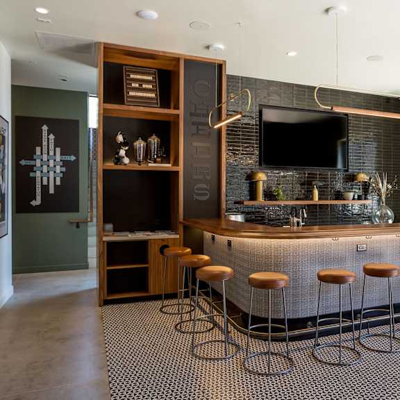 a modern bar area with a dark counter and stools.