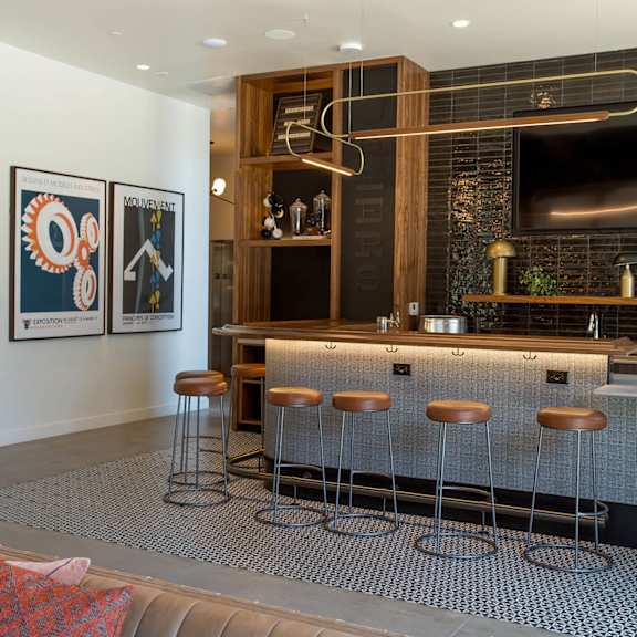 a bar area with a grey sofa and a black tiled wall.