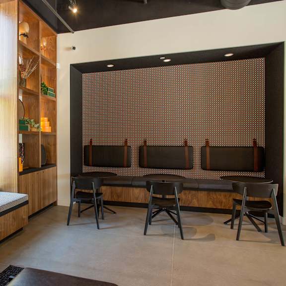a room with a bench, chairs and a window.