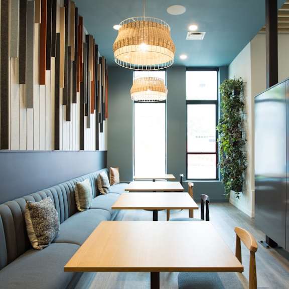 a long wooden table is in the middle of a room with a blue wall and a hanging light fixture.