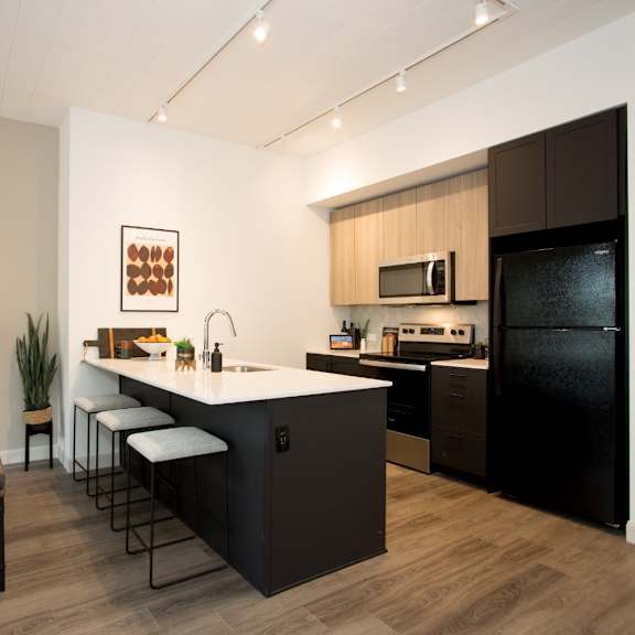 a modern kitchen with dark brown cabinets and a black refrigerator.