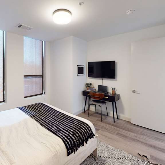 a bedroom with a bed, desk, and window.