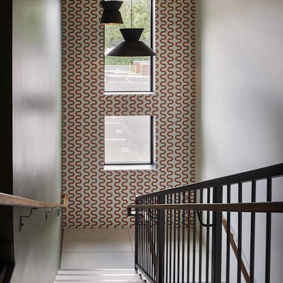 a hallway with a black railing and a wallpapered wall with a pattern of circles.