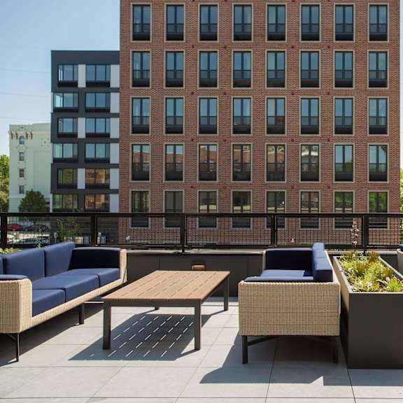 a patio with a table and chairs is in front of a brick building.