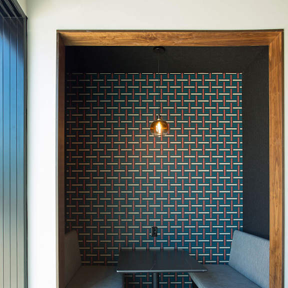 a black and white tiled wall with a wooden frame and a table and bench in front of it.