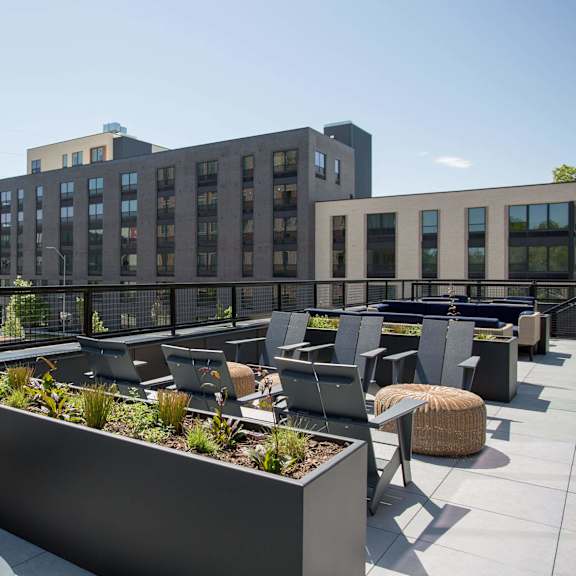 a rooftop patio with a planter box and chairs.