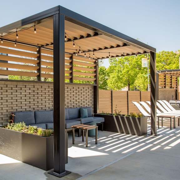 a modern outdoor seating area with a brick wall and a pergola.
