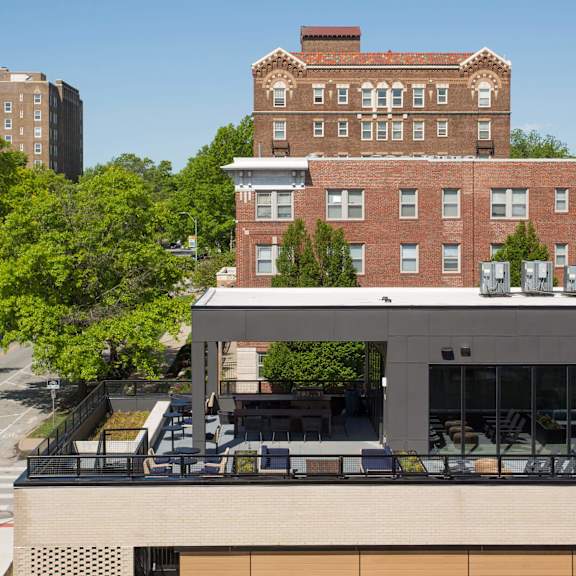 a modern building with a balcony is in front of a red brick building.