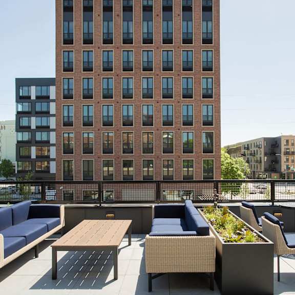 a large red brick building with a balcony containing a table and chairs.