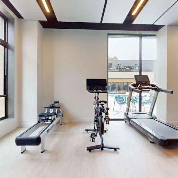 a gym with treadmills, elliptical machines, and a stationary bike.