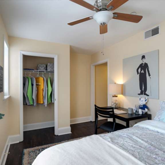 a bedroom with a bed, chair, and a ceiling fan.