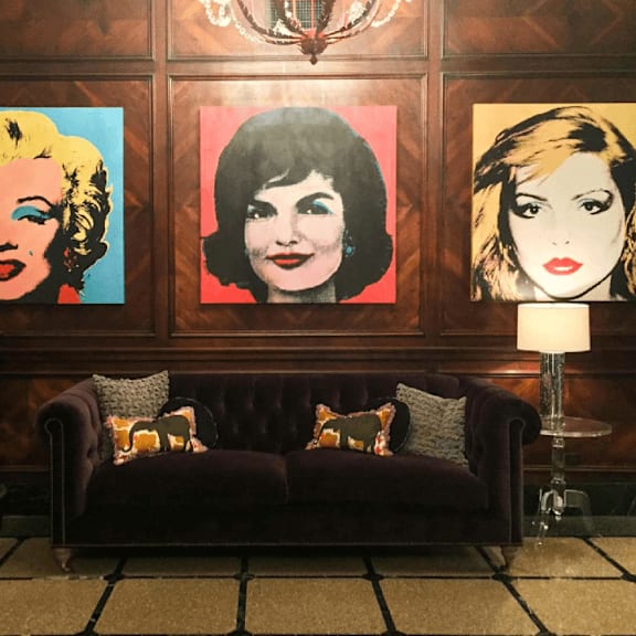 three portraits of women are displayed on a wall above a couch.