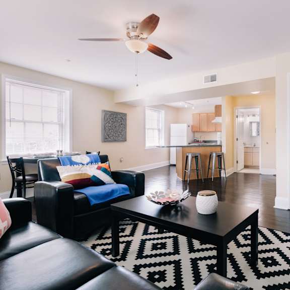 a living room with a black and white rug and a ceiling fan.