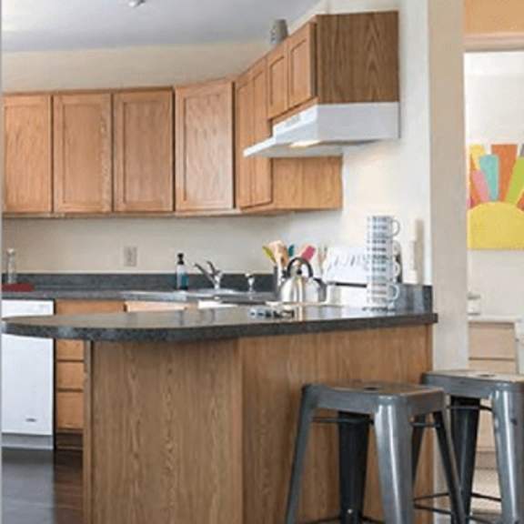 a kitchen with wooden cabinets and a bar stool.