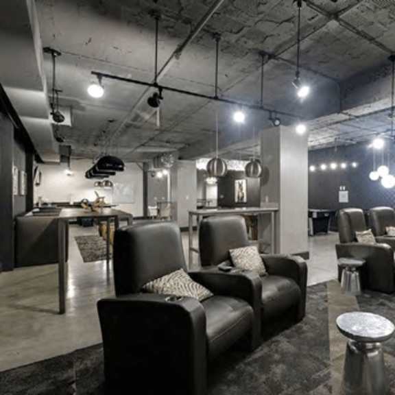 a black leather sofa with a pillow sits in a room with a grey carpet.
