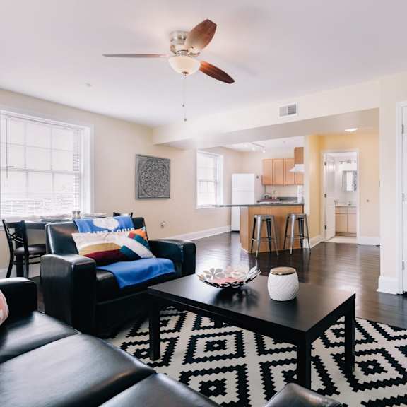 a living room with a black and white rug and a ceiling fan.
