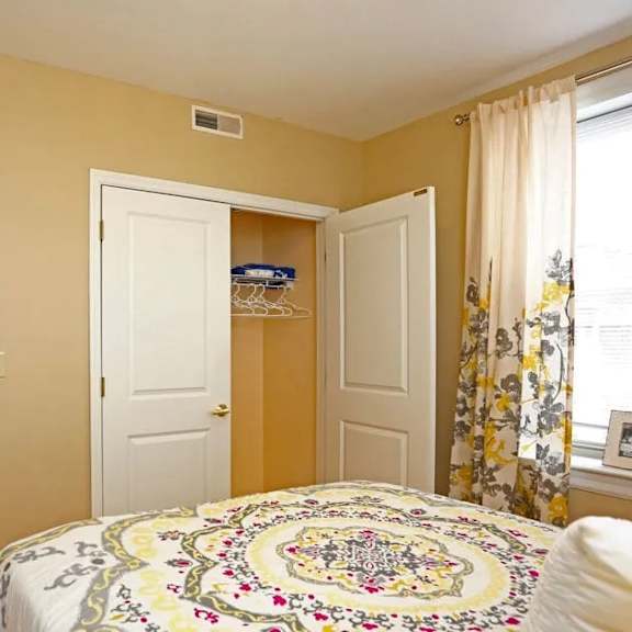 a bedroom with a bed, two closets, and a window.