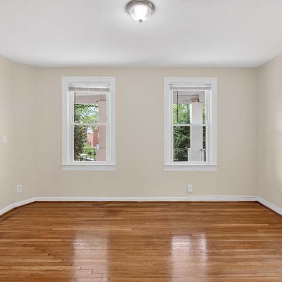 a room with wooden floors and two windows.