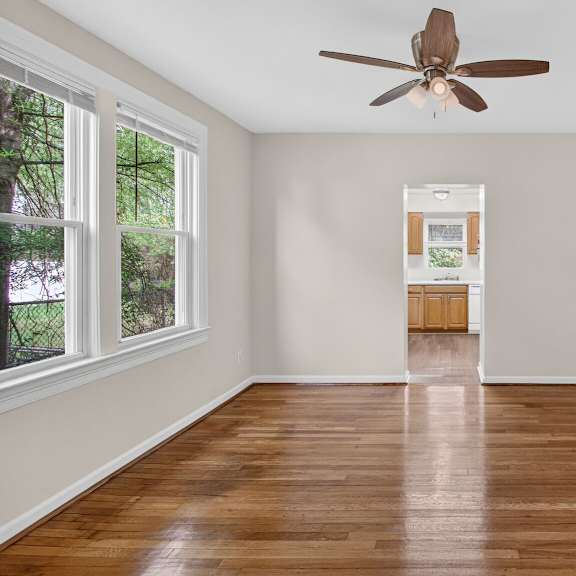 a room with a ceiling fan and wooden flooring.