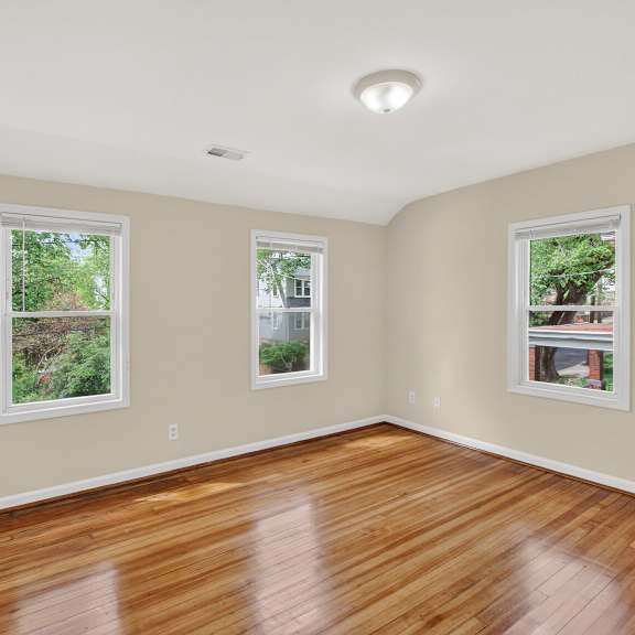 a room with wooden floors and three windows.