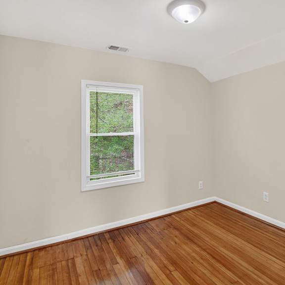 a room with a window and wooden floors.