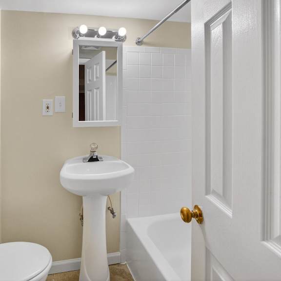 a white bathroom with a toilet, sink, and tub.