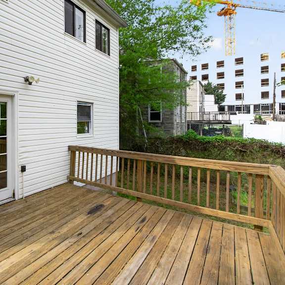 a wooden deck with a white house and a crane in the background.