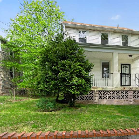 a white house with a black iron railing on the front porch.