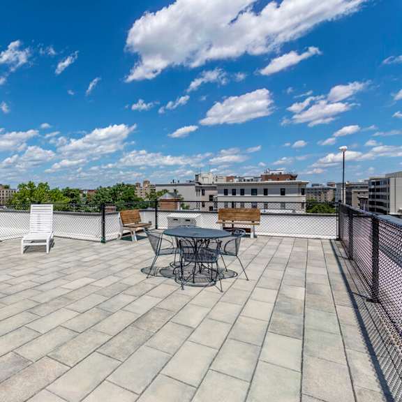 a rooftop patio with a table and chairs overlooking a cityscape.