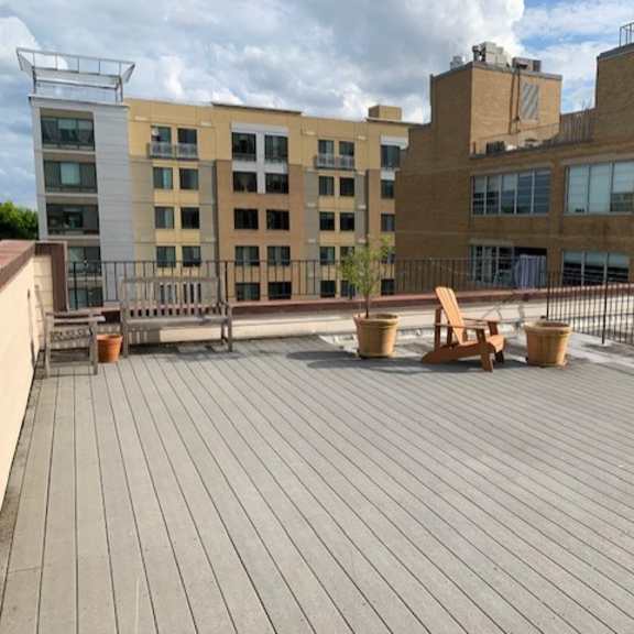 a rooftop patio with wooden decking and a few chairs and tables.