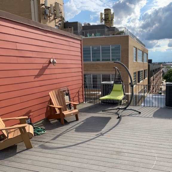 a wooden deck with a green chair and a yellow umbrella.