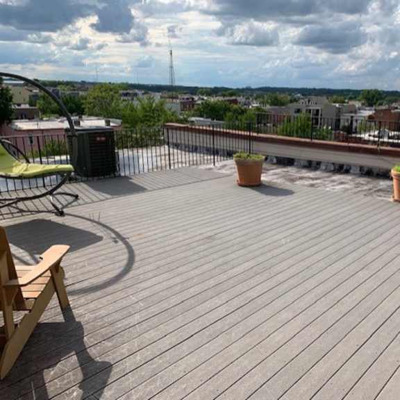 a wooden deck with a table and chairs overlooking a cityscape.