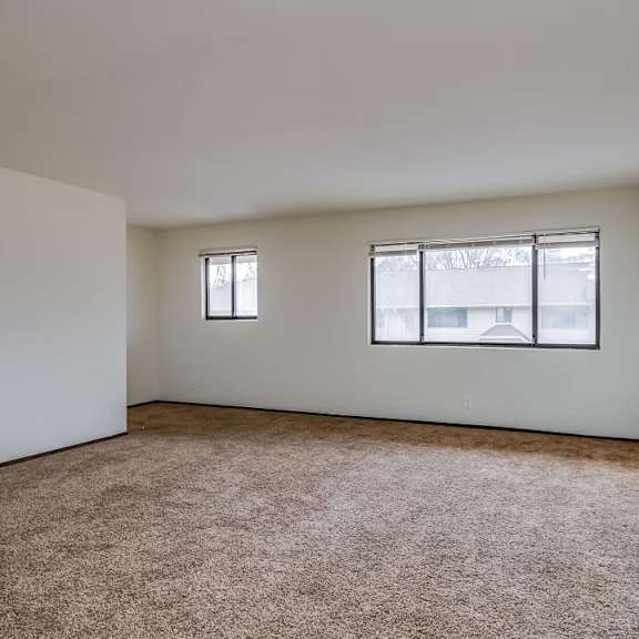a room with a carpeted floor and two windows.