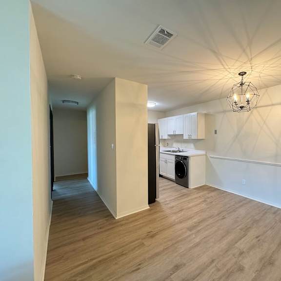 a room with wooden flooring and a chandelier hanging from the ceiling.