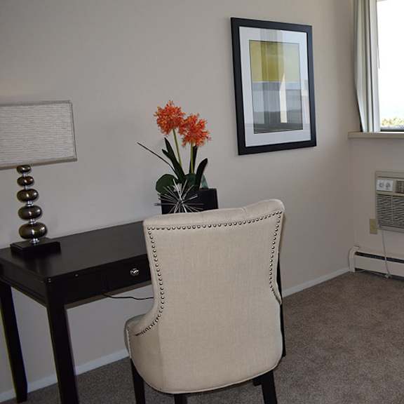a room with a chair and a table with a vase of flowers on it.