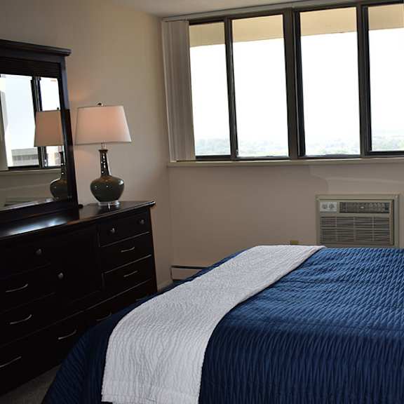 a bedroom with a bed, nightstand, and window.