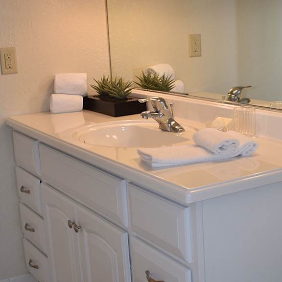a white bathroom with a sink, mirror, and toilet.