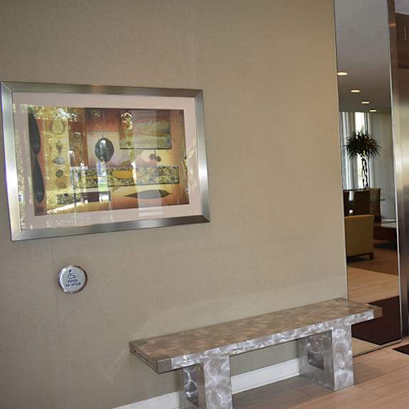 a hallway with a bench, a picture, and a door.