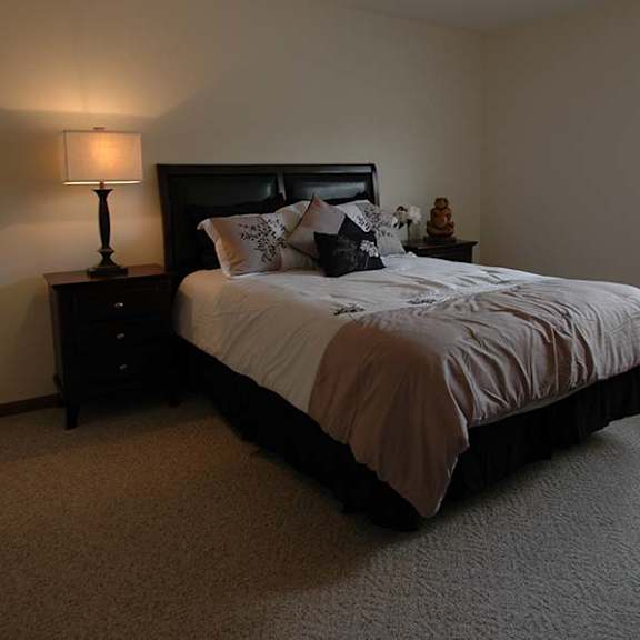 a bedroom with a bed, nightstand, and lamp.