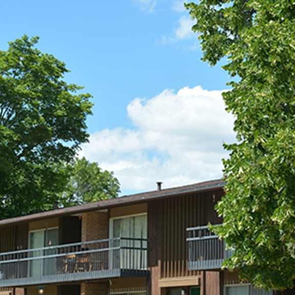 a building with a balcony and trees in front.