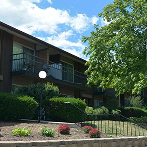 apartment building with a black fence and bushes in front.