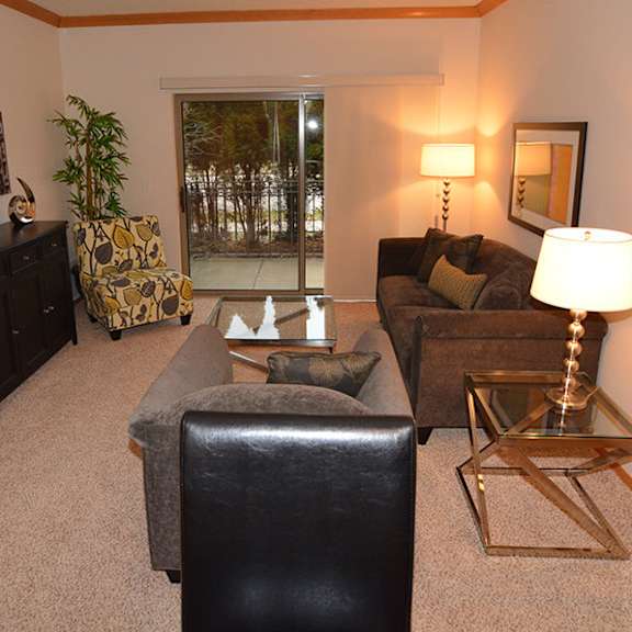 a living room with a black leather chair and a gold side table.